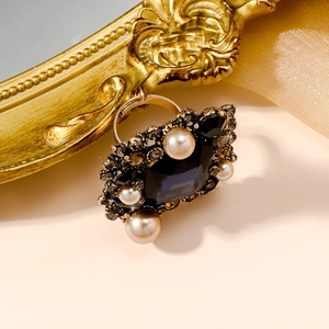 Close-up of vintage palace style ring with dark blue gemstone and white pearls