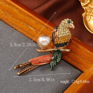 Macro detail of parrot brooch with yellow rhinestones, pink pearl and enamel feathers