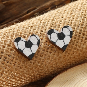 Minimalist heart-shaped wooden stud earrings with soccer ball pattern on burlap surface