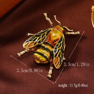 Detailed size view of bee-shaped golden enamel brooch on a silk fabric background