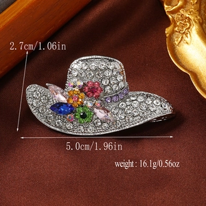 Macro detail of hat-shaped brooch with colorful rhinestones on brown silk background