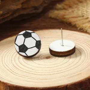 Detailed view of handmade soccer pattern wooden stud earrings on natural wood block