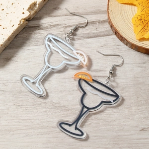 Macro shot of stylish acrylic cocktail glass earrings with lemon slices on wood surface