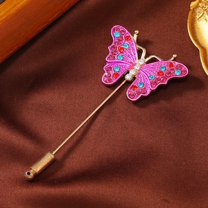 Detail of a purple butterfly pin with colorful rhinestones on a silk background