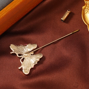 Detail of golden butterfly brooch with textured back and long pin on brown silk