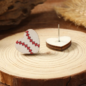 Macro detail of heart-shaped wooden baseball earrings with red stitching on a rustic stand