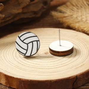 Detail view of round wooden volleyball stud earrings with metal pins on a natural wood surface