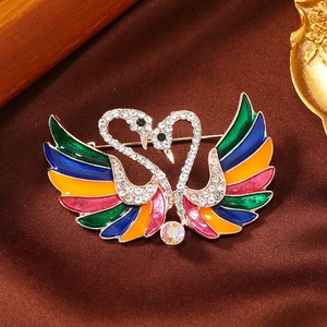 Macro detail of elegant double swan brooch with colorful enamel and crystal inlay