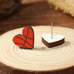 Close-up of heart-shaped basketball pattern wooden stud earrings on a natural wood base