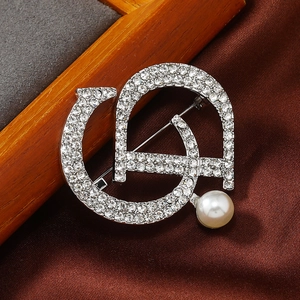 Macro shot of silver letter D brooch with sparkling rhinestones and white pearl detail