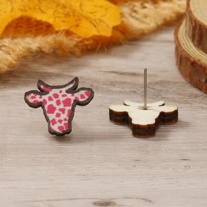 Detalle de pendientes de madera con forma de vaca, patrón rosa y postes de plata hechos a mano