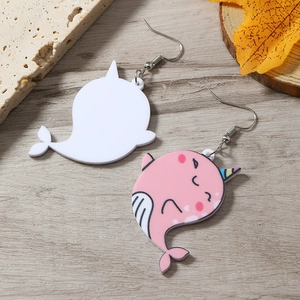 Close-up of pink and white acrylic narwhal earrings with metal hooks on wooden surface