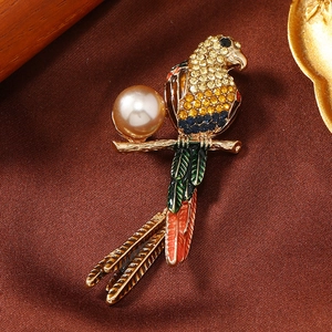 Close-up of a colorful rhinestone parrot brooch with a champagne pearl on silk