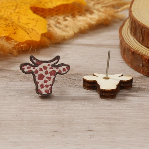 Vista detallada de pendientes de madera con forma de vaca y decoración otoñal
