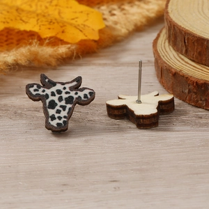 Primer plano de pendientes con forma de vaca y estampado manchado en fondo de madera