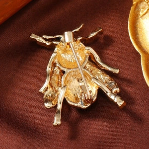 Detailed back view of a golden bee brooch showing the secure safety pin fastening mechanism