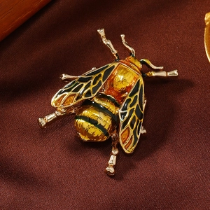 Detailed view of honey bee brooch with golden finish and enamel detailing on silk fabric