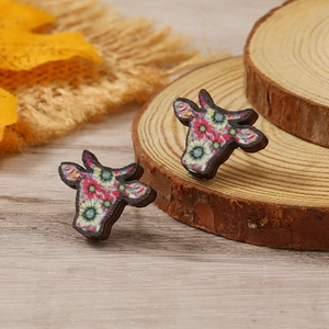 Pendientes de madera en forma de toro con diseño floral sobre madera rústica