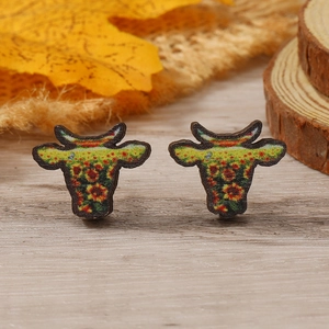 Detalle de pendientes con forma de toro y estampado de girasoles en fondo otoñal rústico