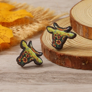Detalle de pendientes de cabeza de vaca en madera con girasoles y flores rojas