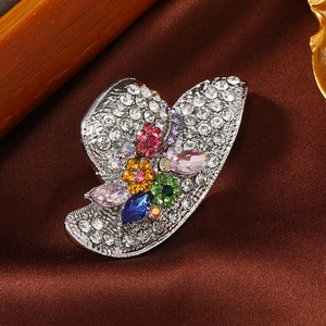 Elegant silver hat brooch with sparkling colorful rhinestones on a silk background