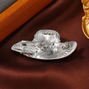Detail view of the silver hat-shaped brooch back with a rotating safety pin buckle