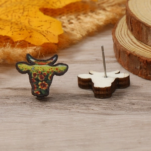 Detalle de pendientes cabeza de vaca con diseño floral y textura de madera