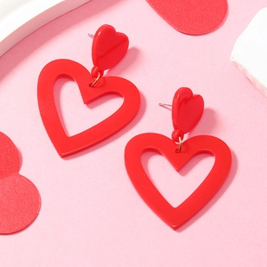 Detail of red acrylic double heart drop earrings with smooth finish and metal stud