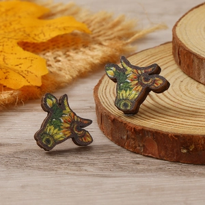 Detalle de pendientes de madera con forma de toro y girasoles sobre fondo rústico
