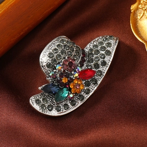 Macro shot of elegant hat-shaped brooch with colorful rhinestones on vintage silver alloy