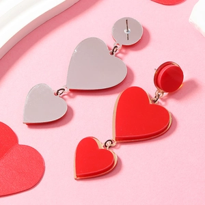 Detail of red acrylic heart earrings showing front red surface and silver mirror back