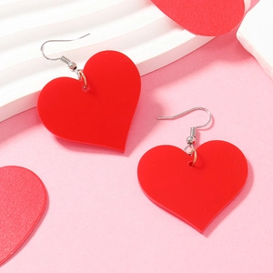 Detailed view of red acrylic heart earrings on a wavy white stand for a romantic look