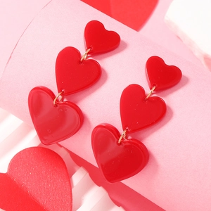 Macro shot of red heart-shaped acrylic dangle earrings with golden chain links