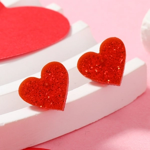 Detailed macro view of heart-shaped red glitter earrings on a white display stand