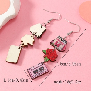 Détail de boucles d'oreilles asymétriques en bois avec roses et imprimé de cassette