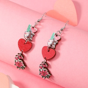 Détail de boucles d'oreilles en bois avec lapin love, cœur rouge et fleurs