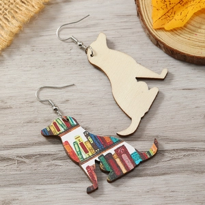 Dettaglio di orecchini in legno a forma di cane con stampa libreria e trama in legno naturale