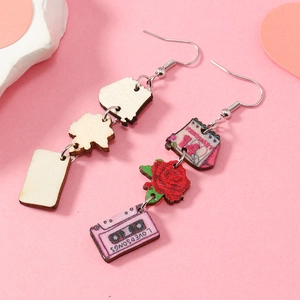 Détail de boucles d'oreilles en bois avec rose peinte, flacon de parfum et cassette Love Songs
