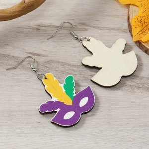 Gros plan de boucles d'oreilles en bois avec masque de carnaval et plumes colorées