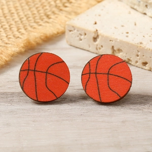 Macro shot of orange wooden basketball stud earrings with realistic printed texture