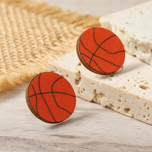 Macro shot of basketball wooden stud earrings on stone and burlap background