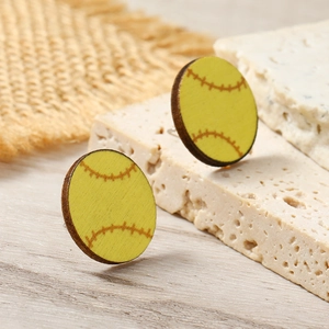 Macro view of wooden softball stud earrings with yellow finish and red stitching details