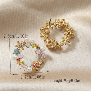 Macro shot of gold floral hoop earrings with white pearls and colorful rhinestones