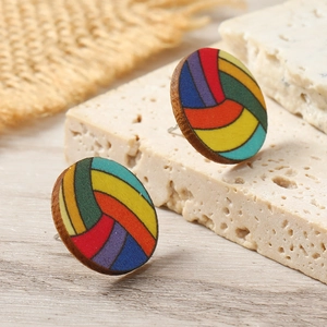 Macro shot of circular wooden rainbow volleyball earrings on a textured stone surface