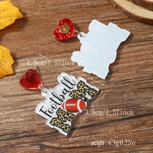 Macro view of acrylic football mom earrings with red glitter hearts and leopard print