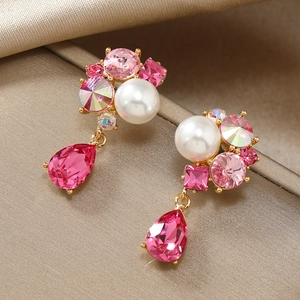 Detail of pink crystal teardrop earrings with white pearl and gold-plated setting