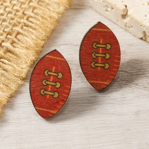 Detail of wooden rugby ball earrings with vintage flame pattern on linen and stone