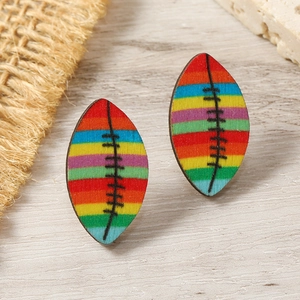 Close-up of rainbow striped wooden rugby earrings on a natural wood and burlap surface