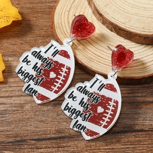 Detail showing acrylic heart rugby earring with 'I'll always be his biggest fan' print
