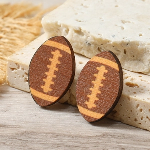 Handcrafted wooden rugby ball earrings with natural grain texture on a stone display